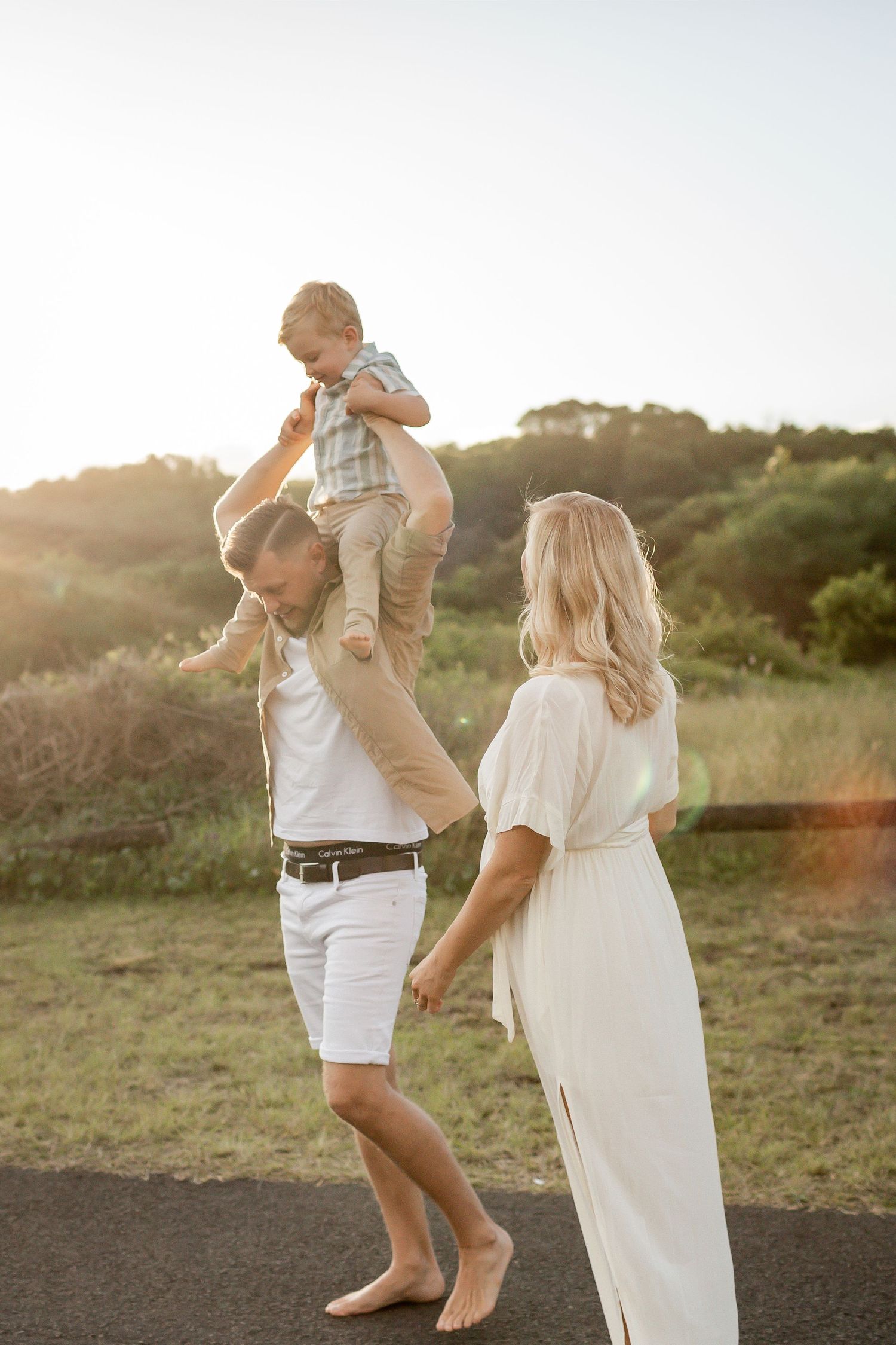 Playful family moment in outdoor setting with natural sunlight and greenery.