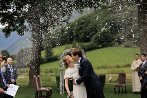 A romantic outdoor wedding ceremony with confetti fluttering in the air against a backdrop of green rolling hills.