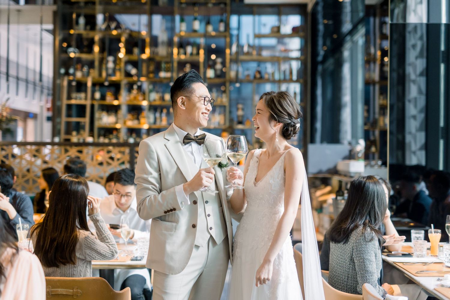 A couple in formal attire celebrates with champagne glasses in a restaurant setting.