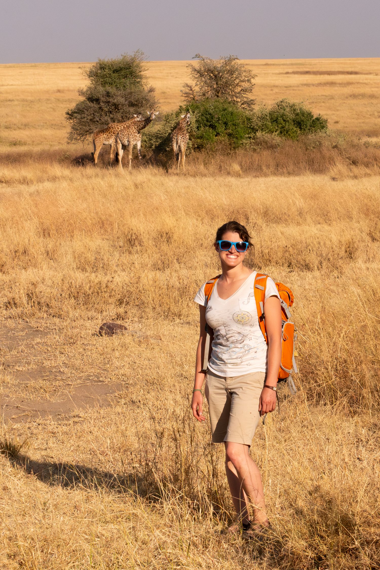 Leah Ramuglia photographed in Serengeti National Park with wild giraffes in the background of Tanzania in East Africa.