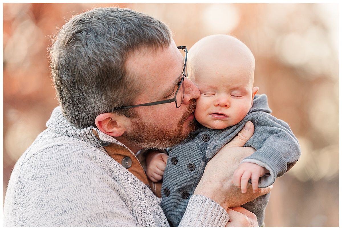 Sweet photo of father kissing baby son with beautiful bokeh background in fall Starkey Park Zionsville Indiana