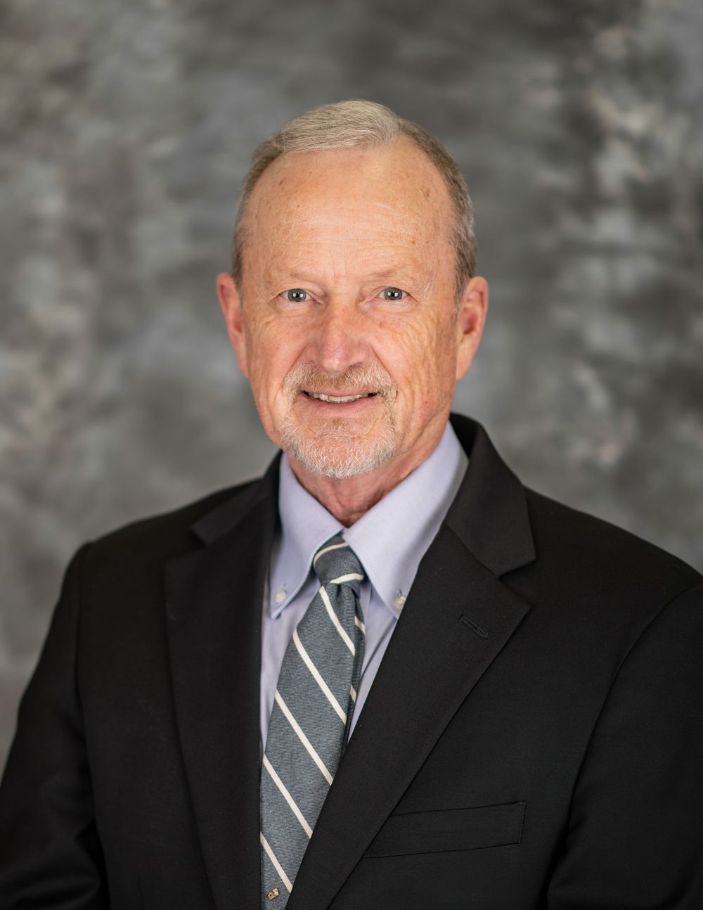 Professional headshots of person in business attire against grey background.