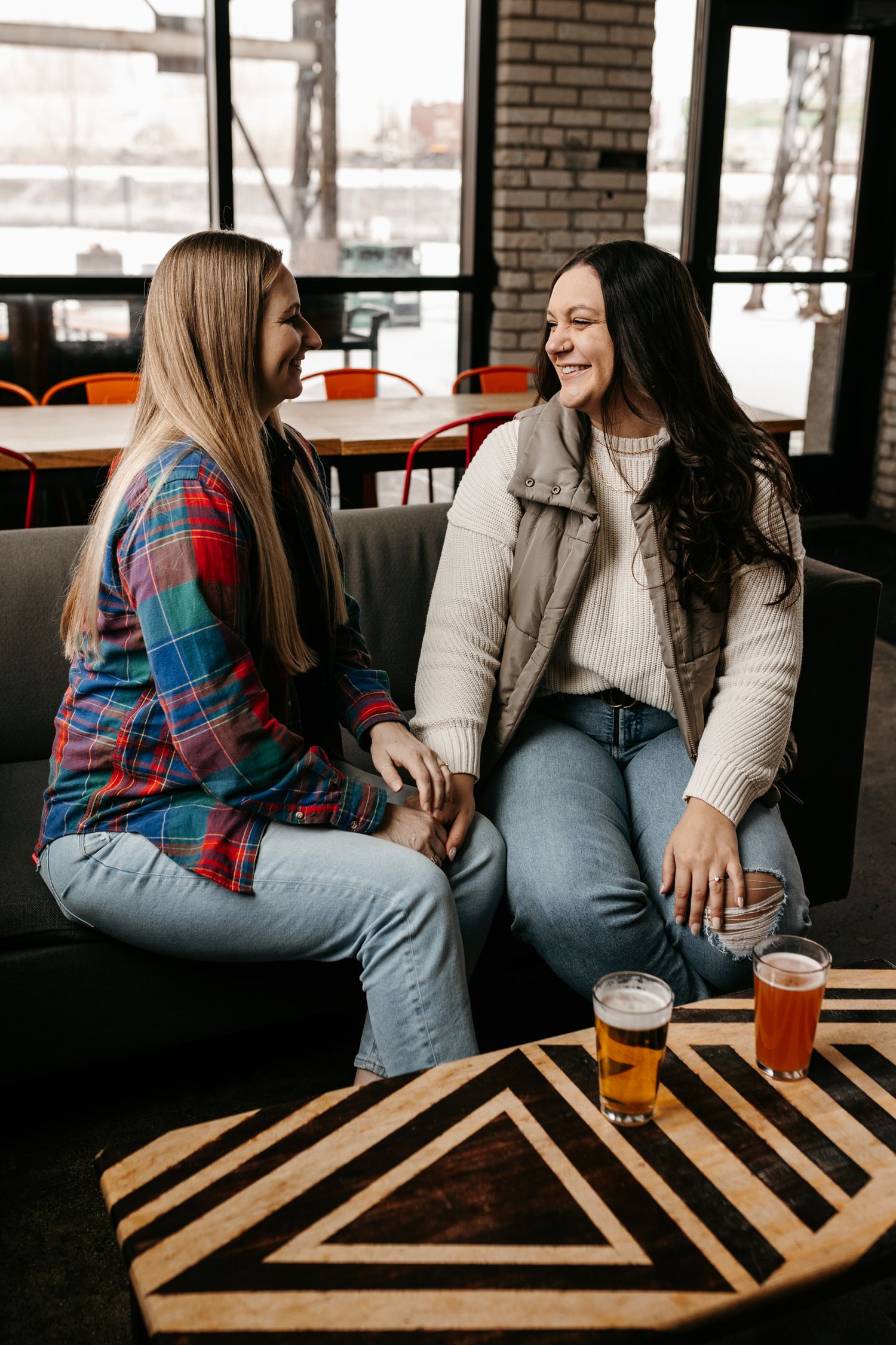 Friends sharing beers and conversation on a patterned coffee table in an industrial brick setting.