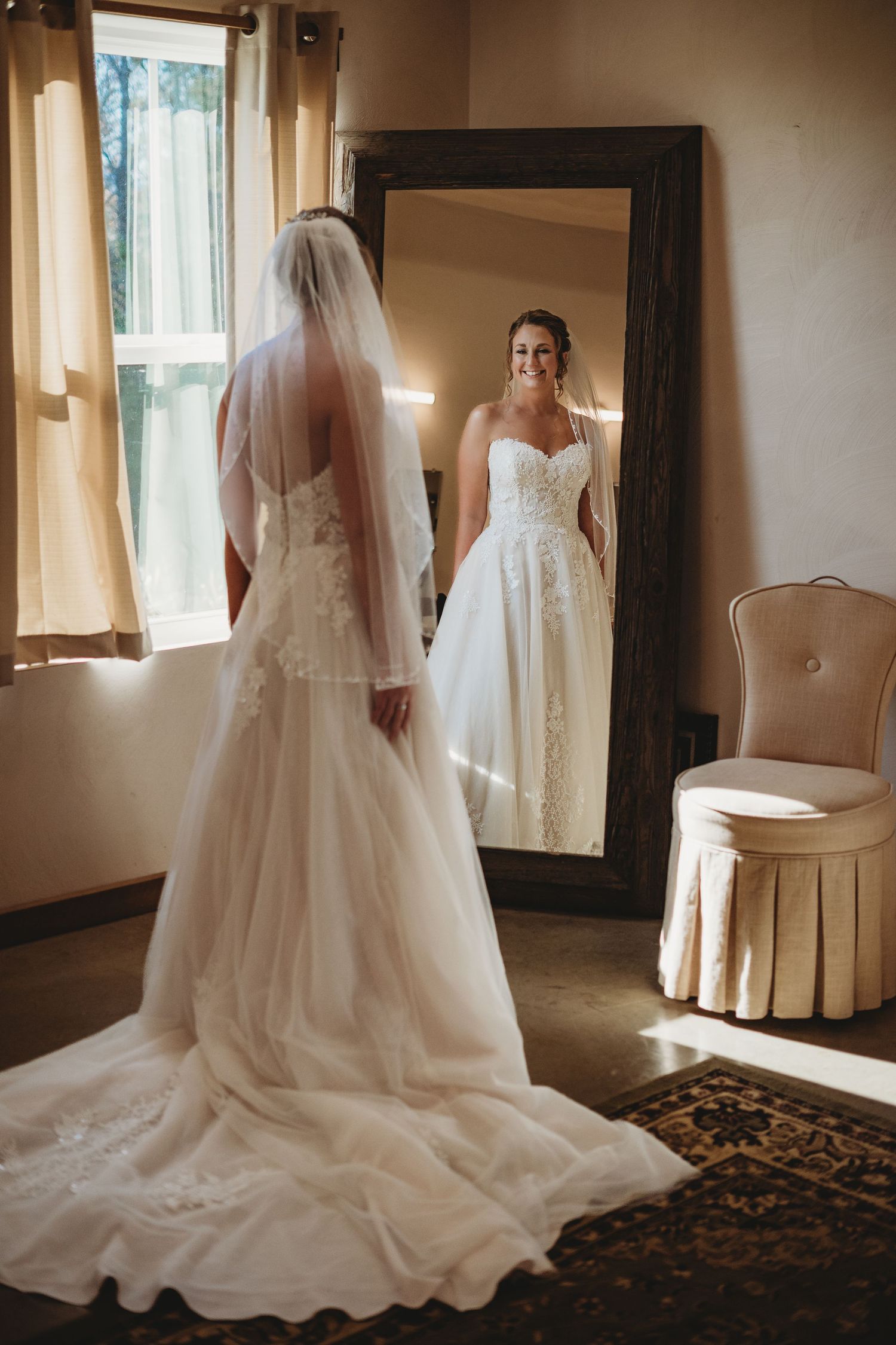 Elegant white wedding dress with long train photographed in sunlit room.