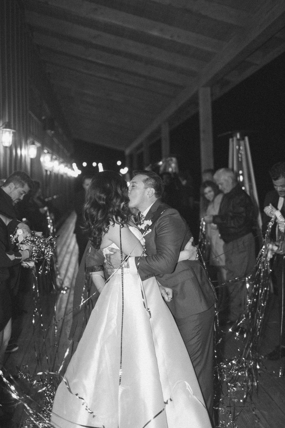 North Star Gatherings, wedding exit with silver streamers, bride and groom kiss. Black and white photo