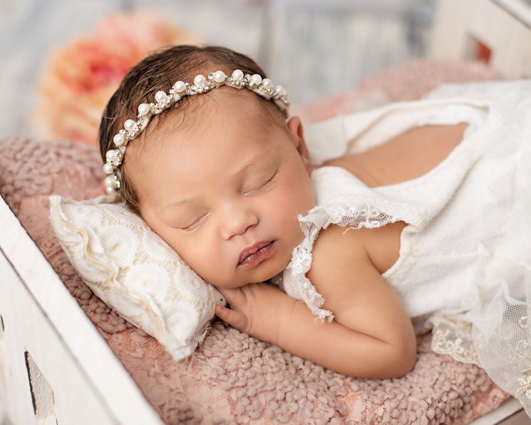 Sleeping infant wearing lace headband on soft pink textured backdrop. springfiedl lakes studio