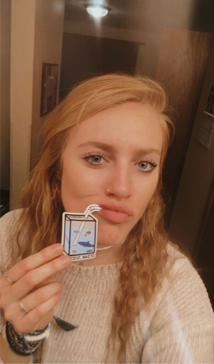 Person holding small sticker against soft lighting in indoor setting.