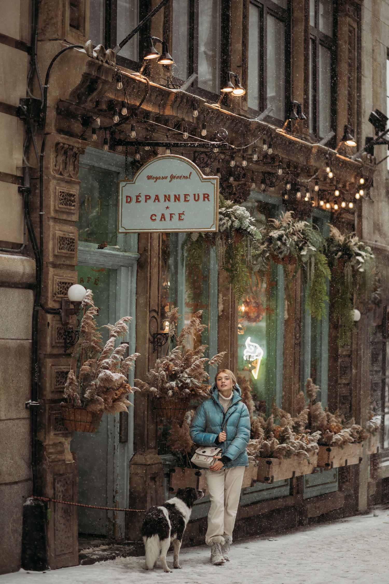 Person walking dog outside Depanneur Cafe during winter with festive decorations.