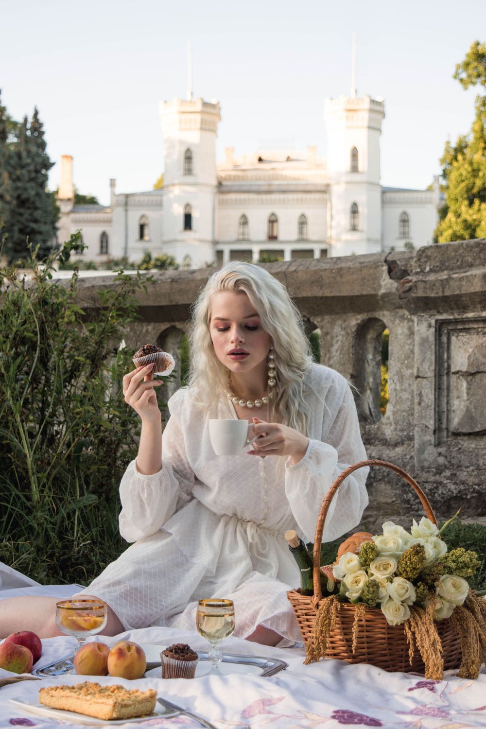 Elegant picnic setup with pastries and flowers in front of a white castle.