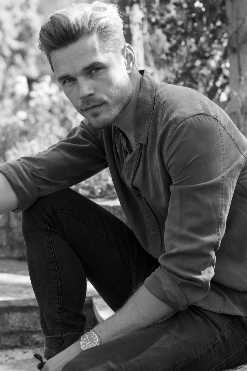 Black and white portrait of person in casual attire sitting outdoors.