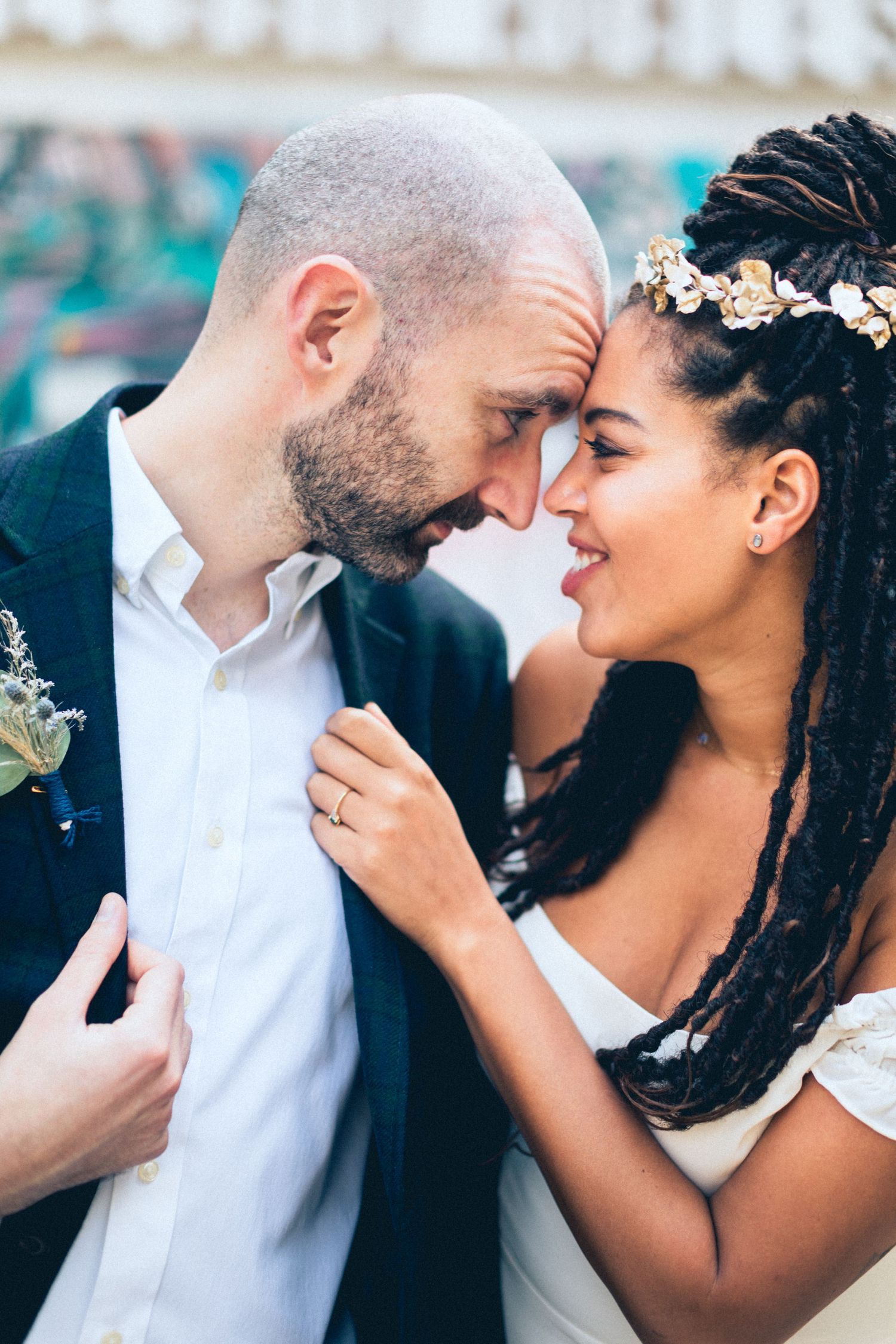 A romantic wedding portrait of a couple sharing an intimate forehead touch with the bride wearing a floral headpiece.