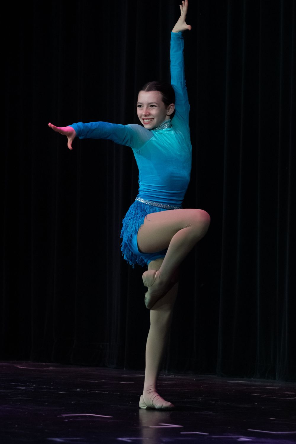 Performer in bright blue costume executes dynamic turning movement.