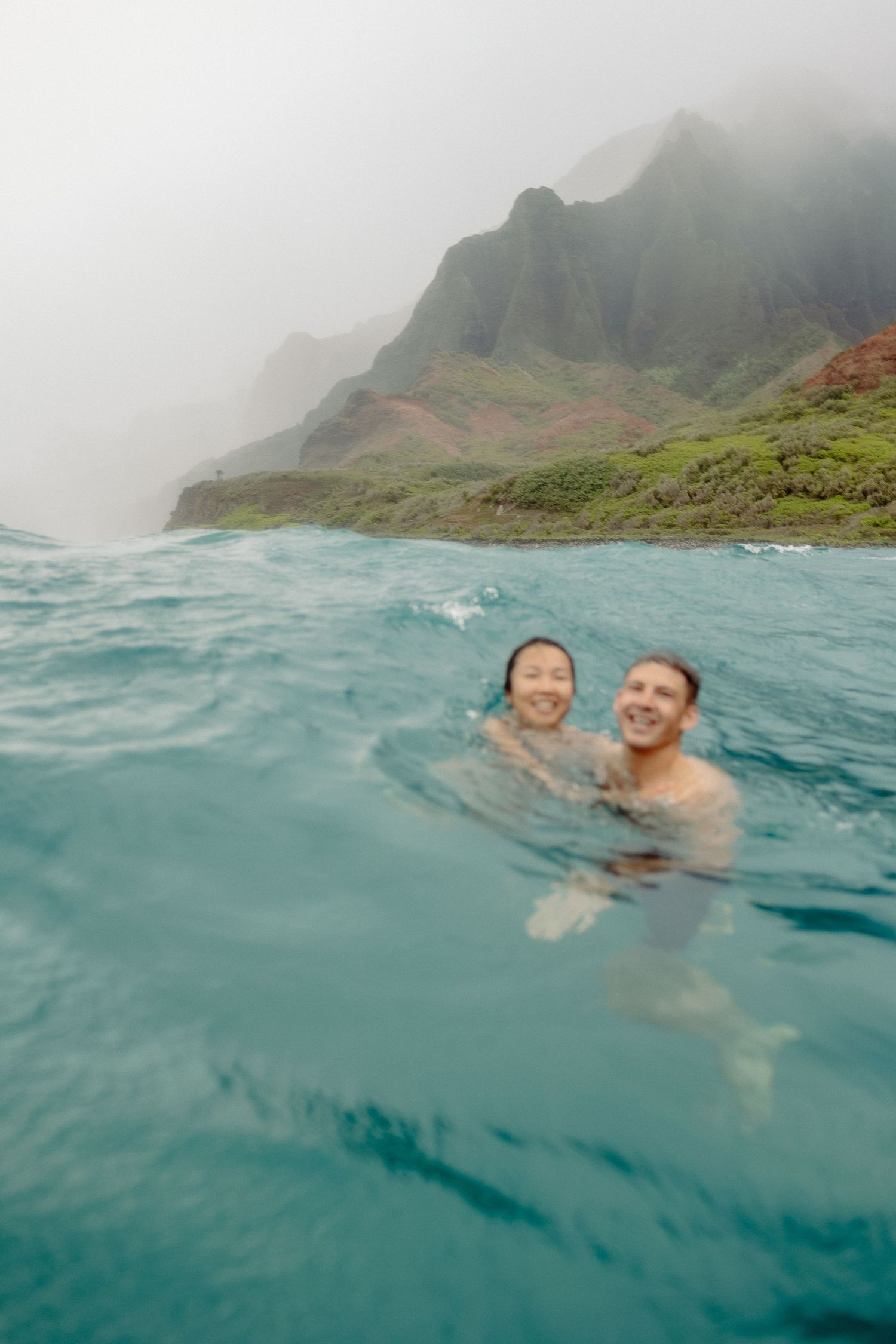 couple swims on their elopement in kauai, napali coast views