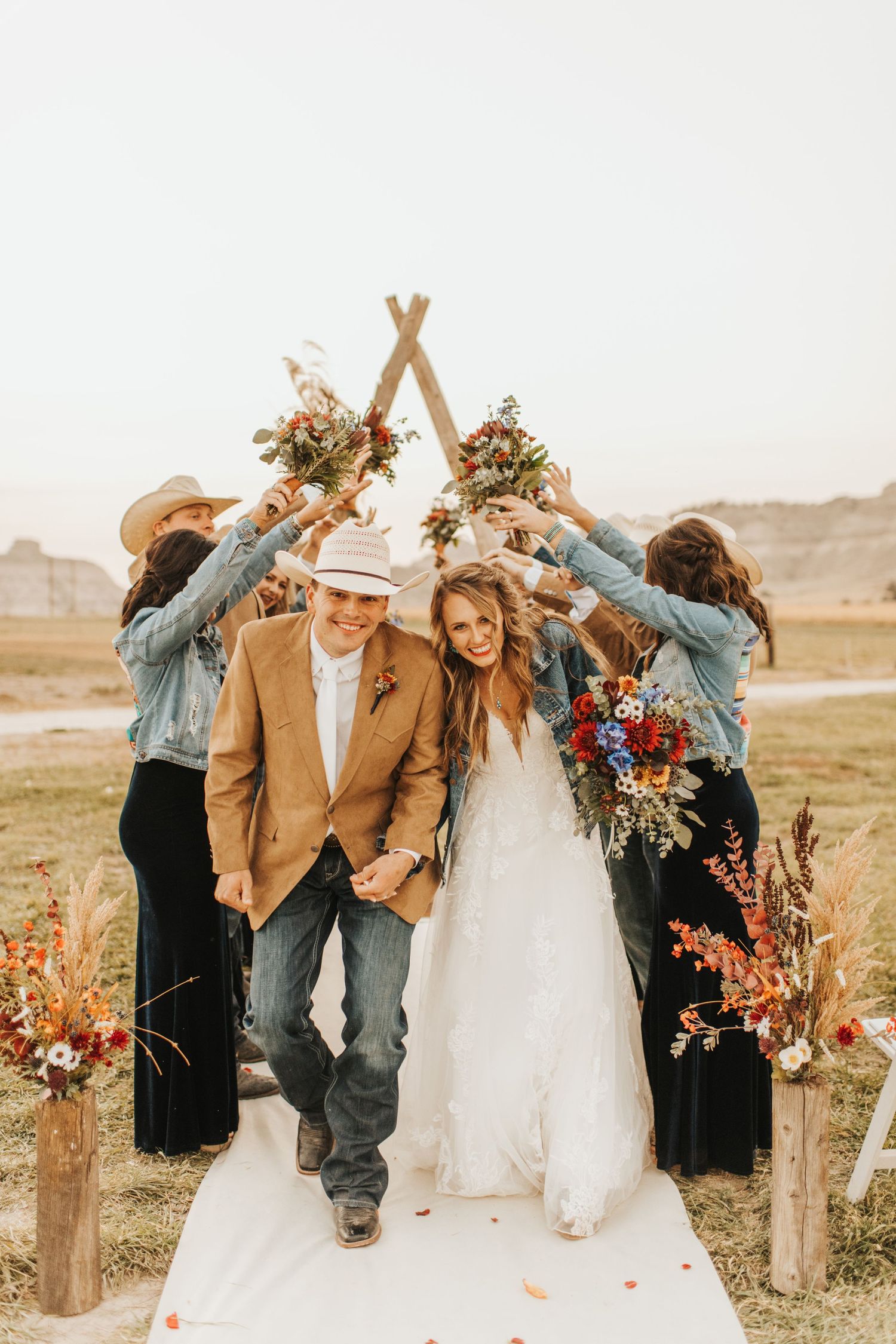 Happy couple walking under a wedding arch made by their friends