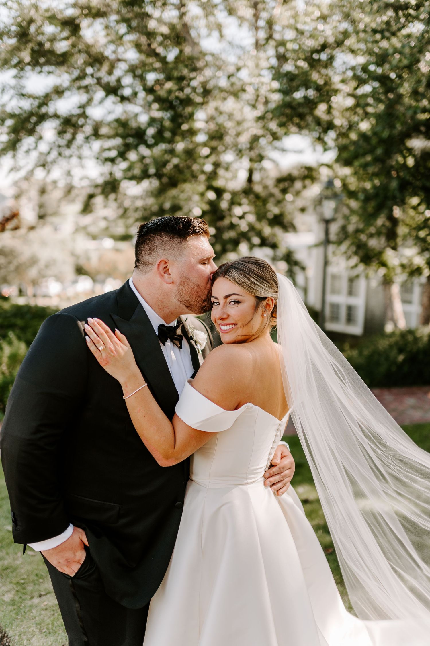 Romantic wedding couple embraces during outdoor photo session.