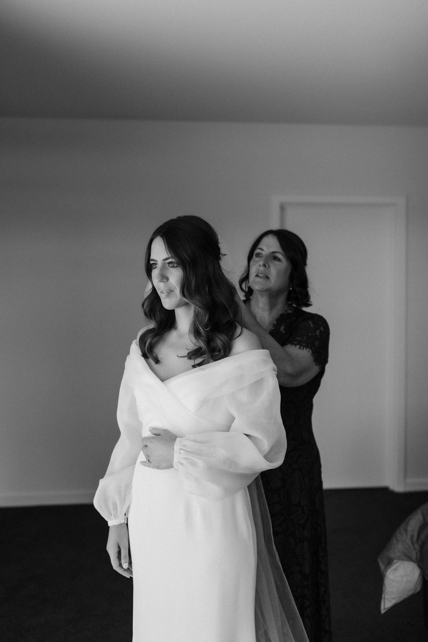 Black and white photo showing final wedding dress adjustments.