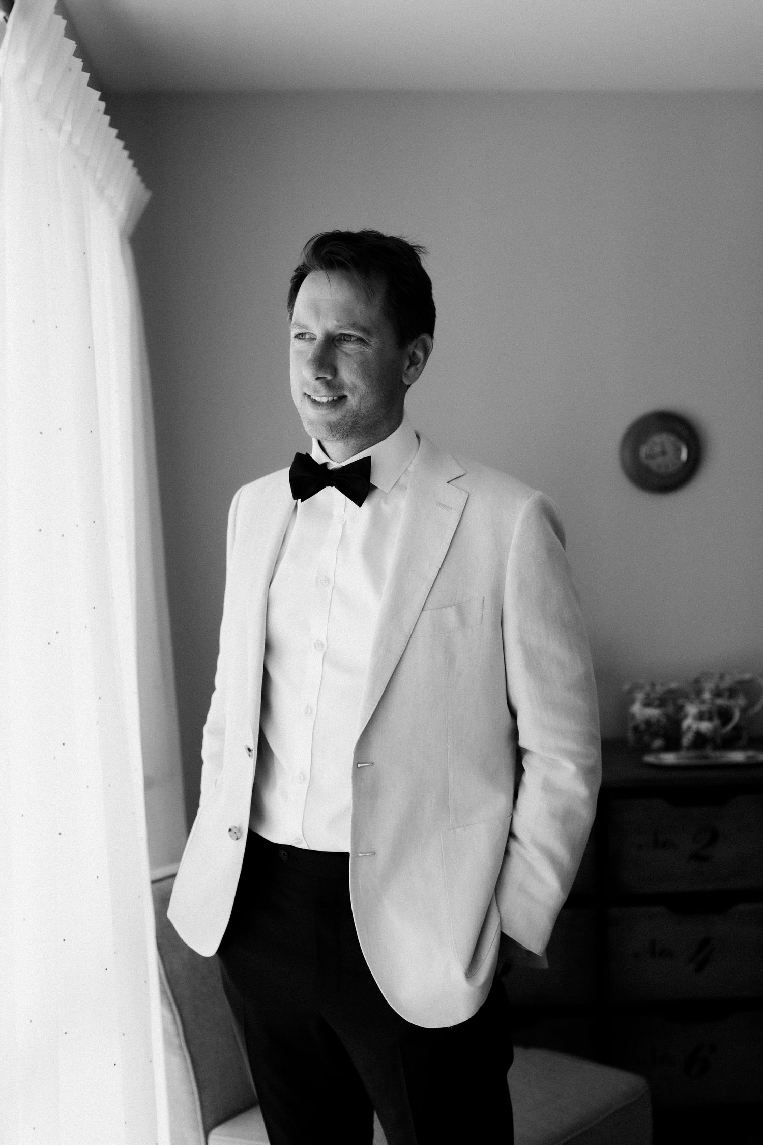 Person in white tuxedo jacket and black bowtie looking to the side.