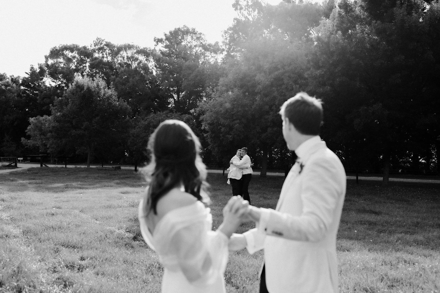 Black and white photo of couple celebrating and dancing in a sunlit field.