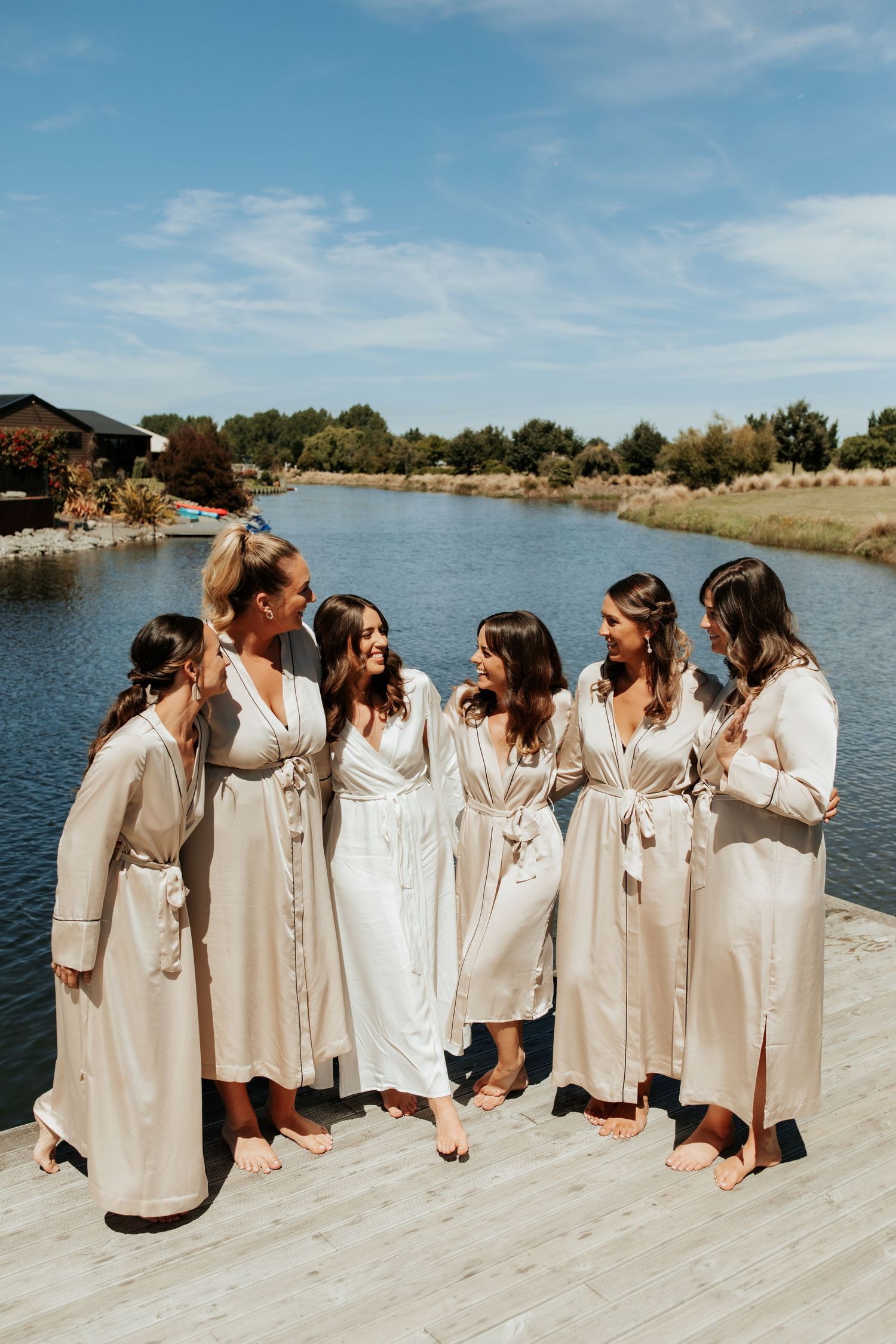 Group wearing matching cream colored robes standing on dock by lake.
