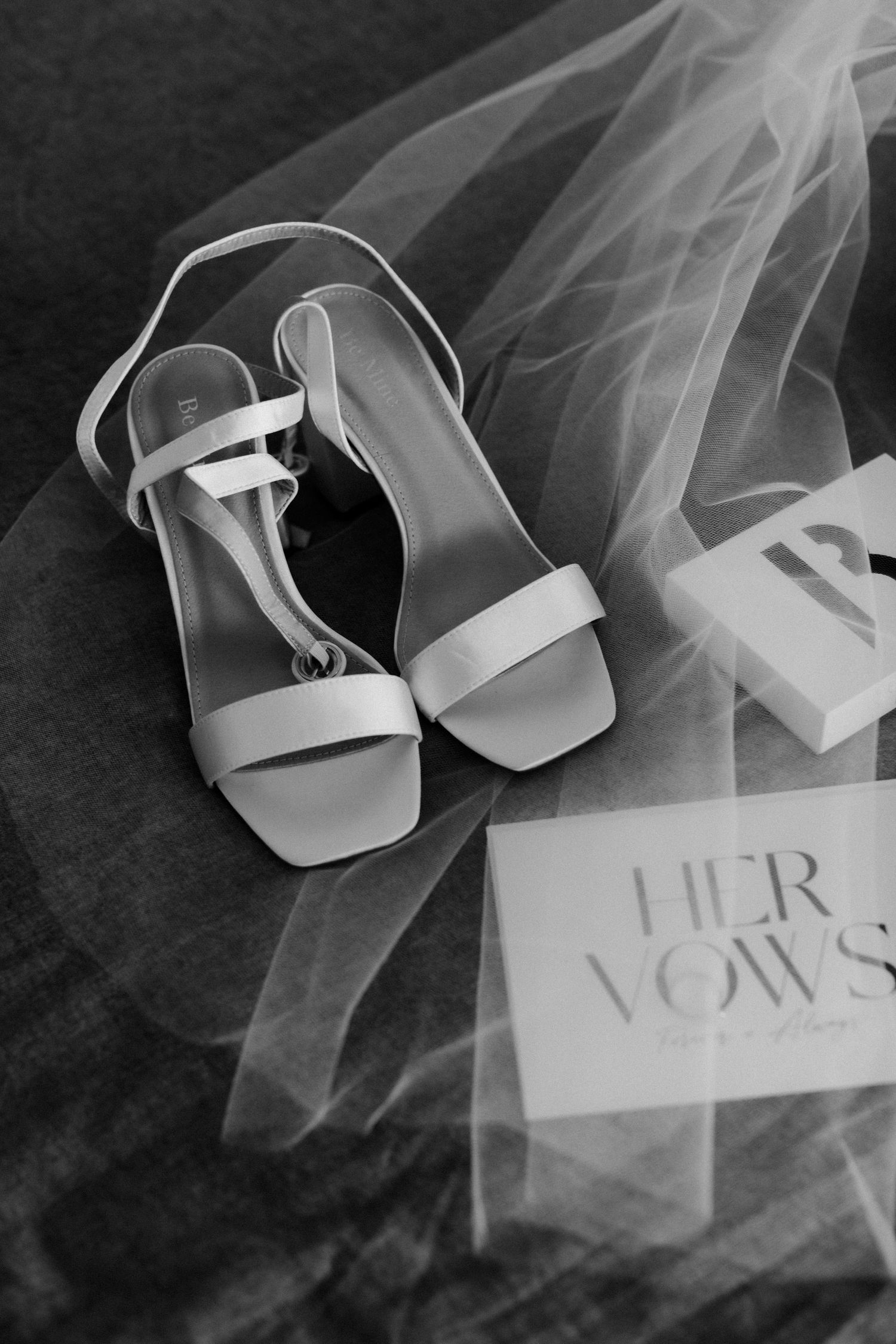 White bridal sandals and vows card with delicate tulle veil.