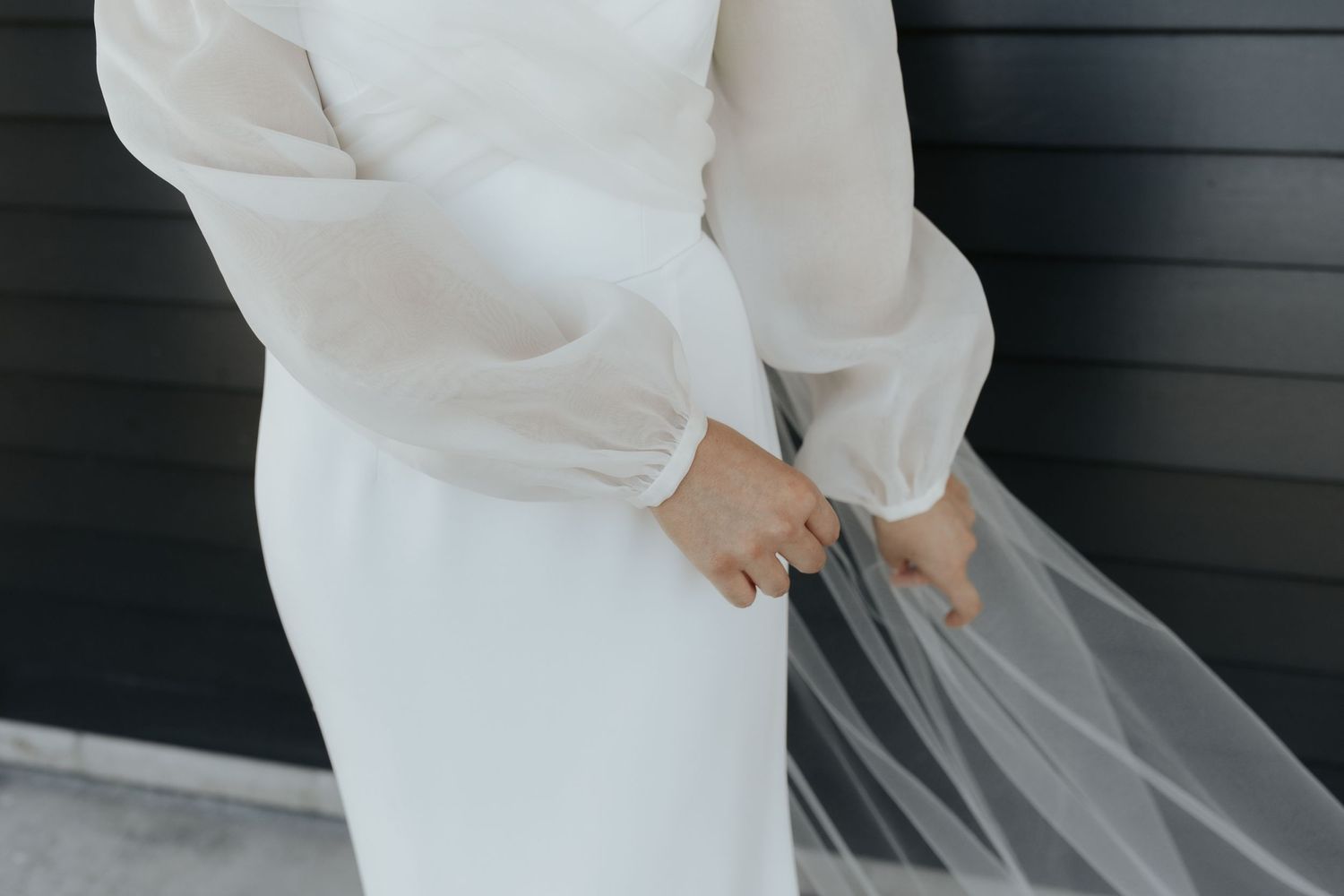 Close-up detail of a modern white wedding dress with long sleeves.