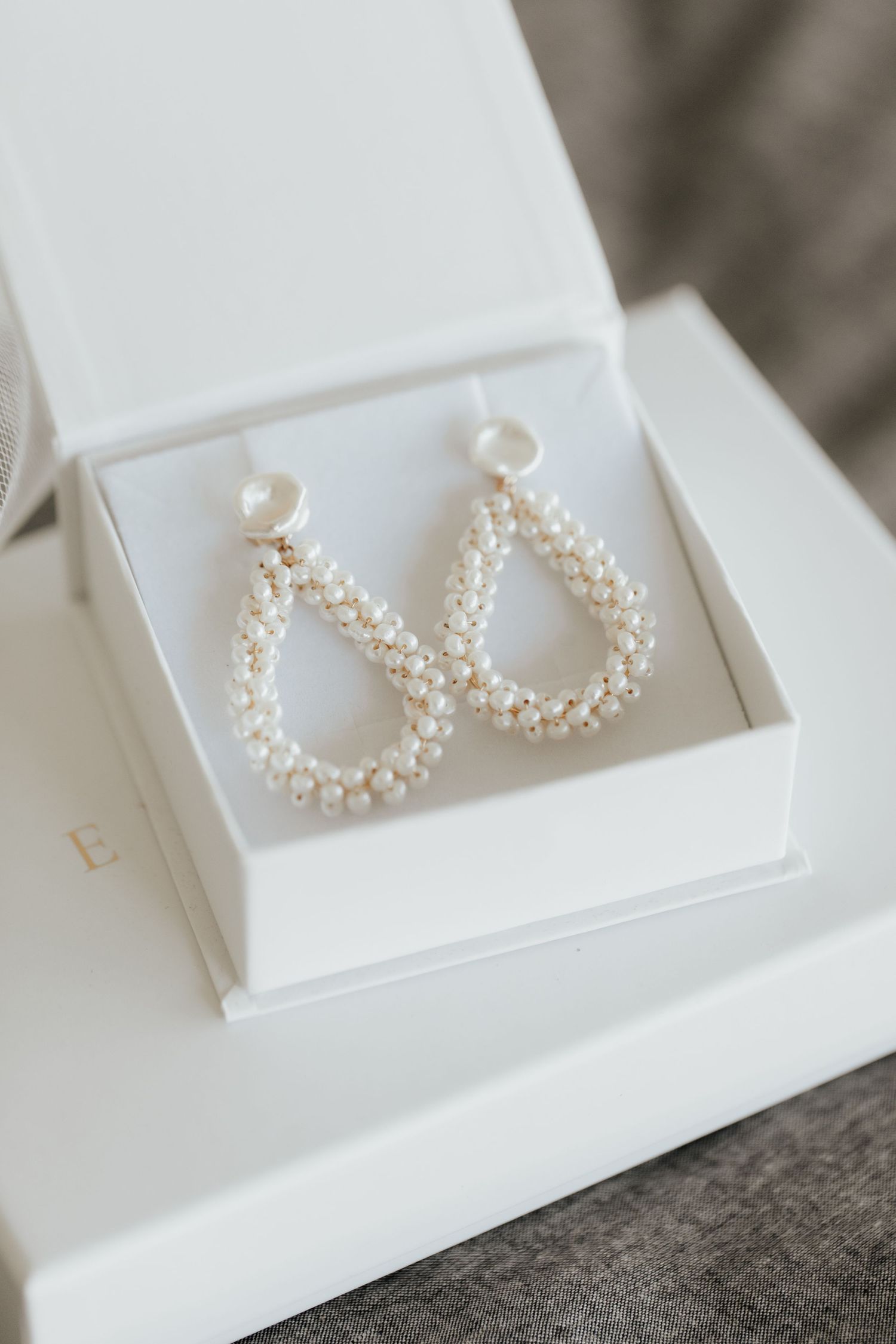 Pearl teardrop earrings displayed in white jewelry box.