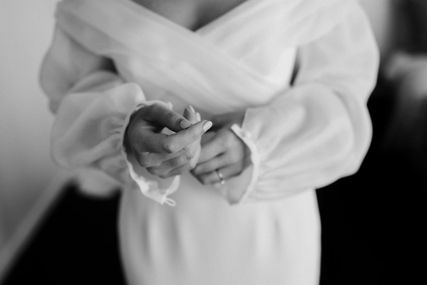 Close-up detail shot of hands holding delicate white fabric.
