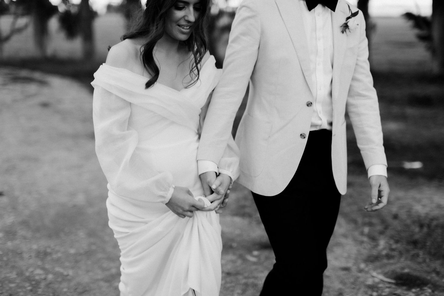 Black and white photo of couple walking together in formal wedding attire.