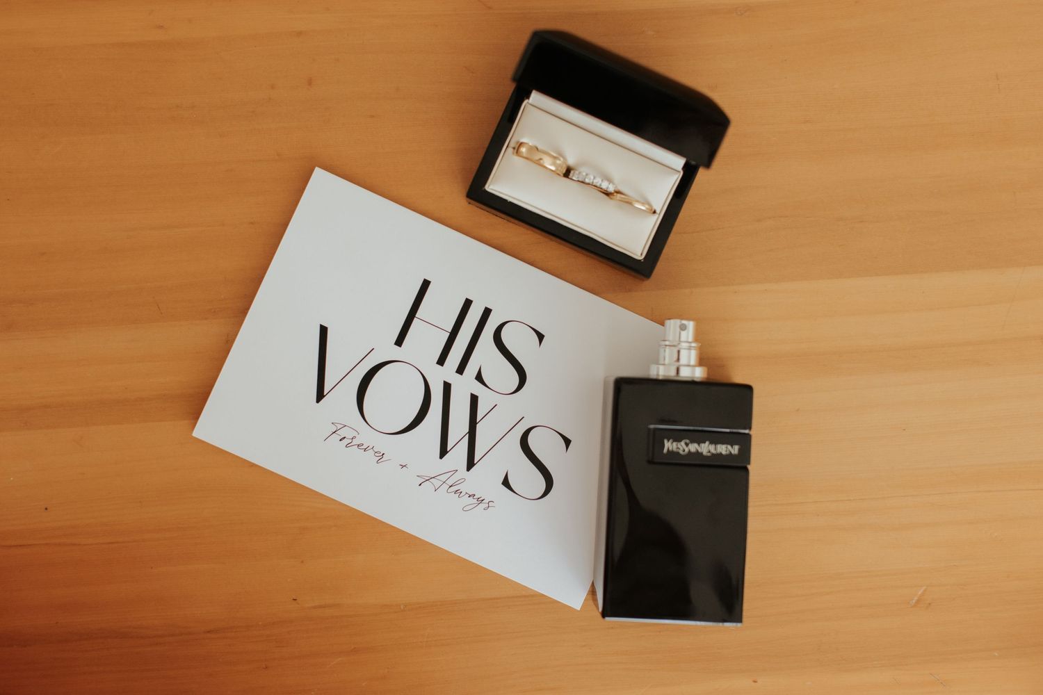 Wedding vows card and black perfume bottle displayed on wooden surface.