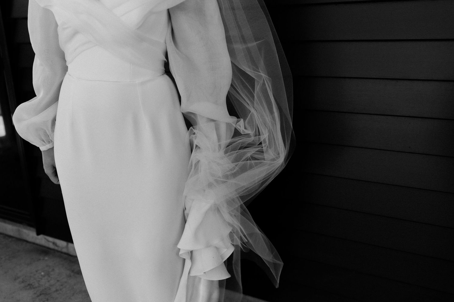 Black and white detail shot of an elegant wedding dress with flowing veil.