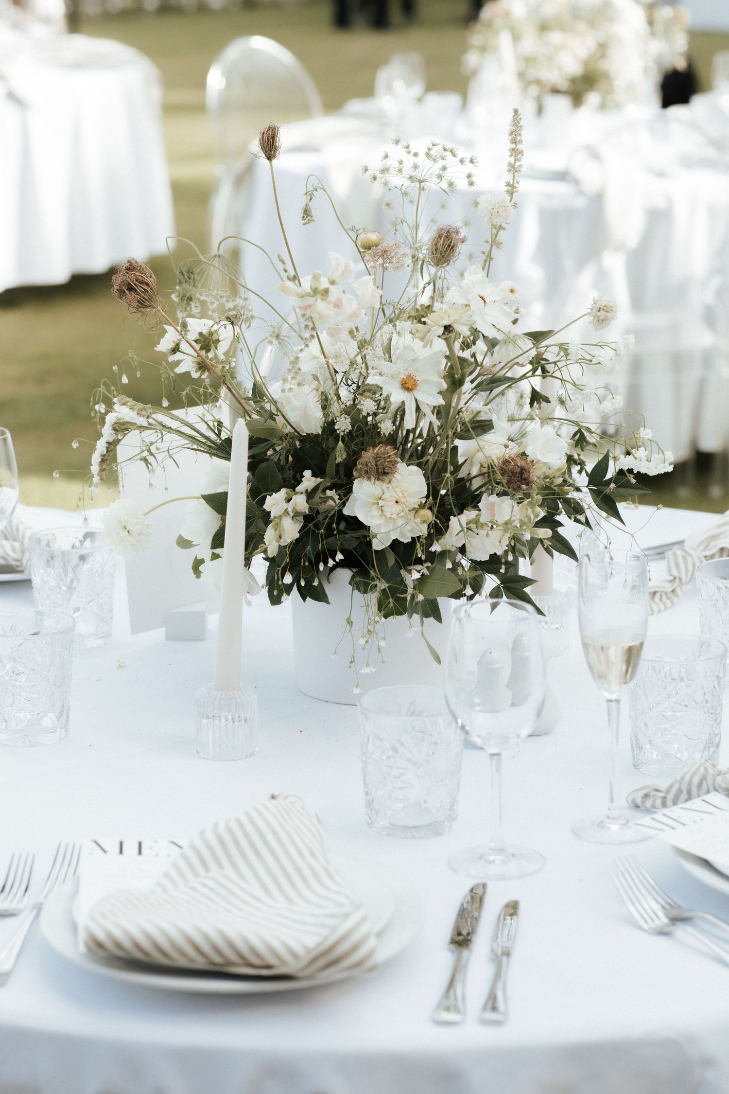 Romantic white floral centerpiece with baby's breath and roses on wedding reception table.