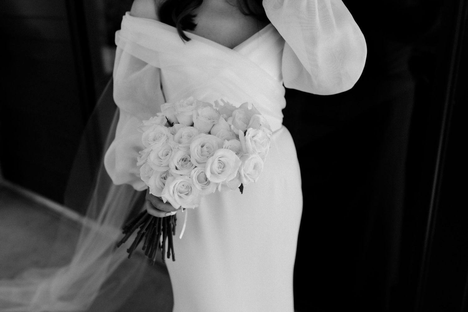 Black and white detail of bride holding classic white rose bouquet.