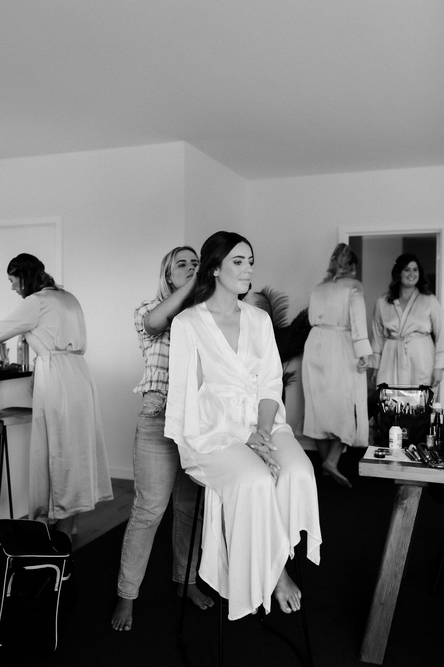 Black and white photo of preparations in a dressing room with people in white robes.