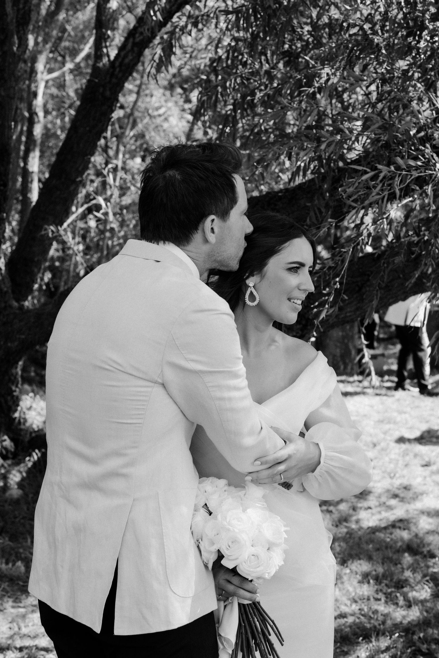 Black and white candid moment between couple during outdoor wedding celebration.