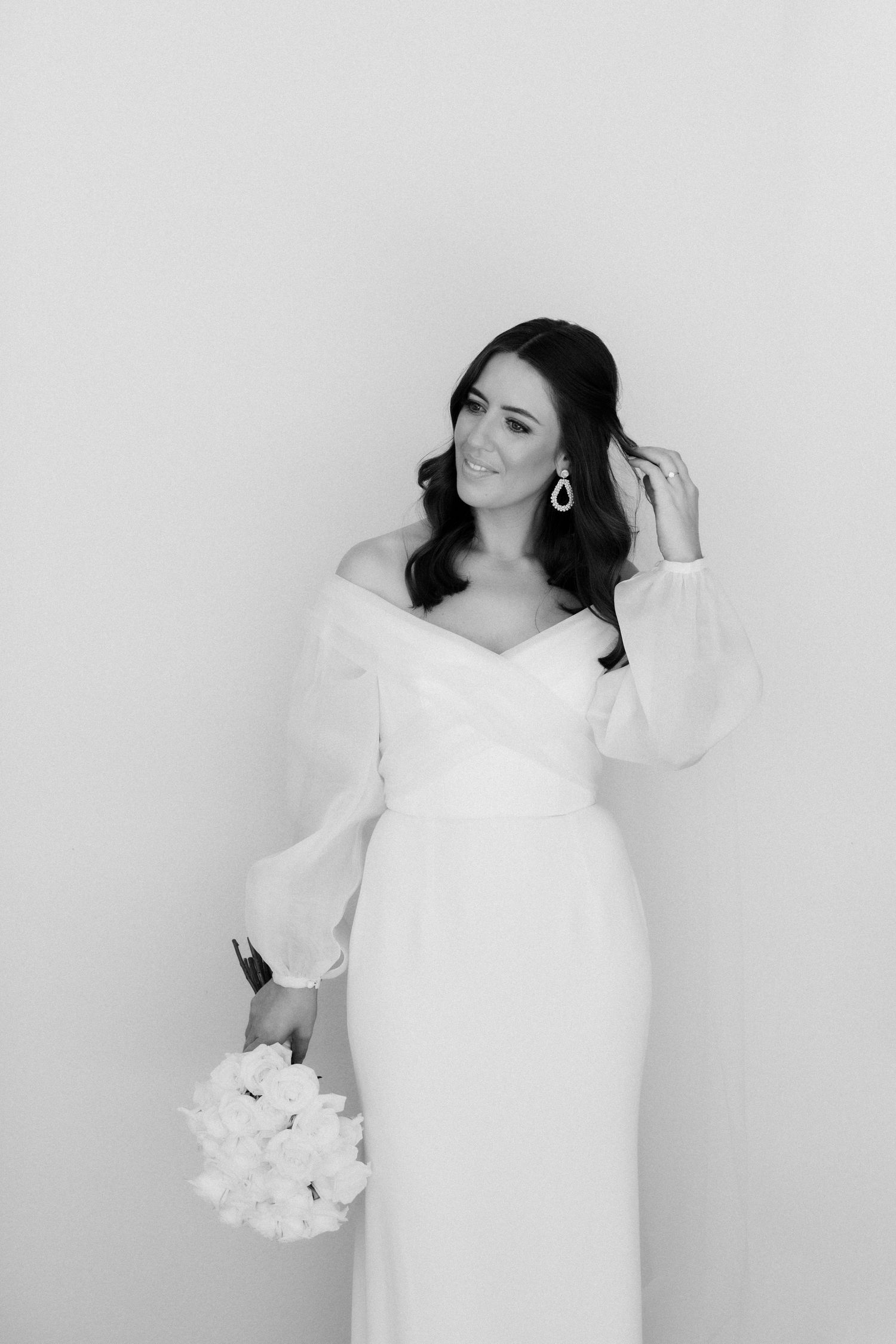 Black and white bridal portrait with off-shoulder gown and statement earrings.