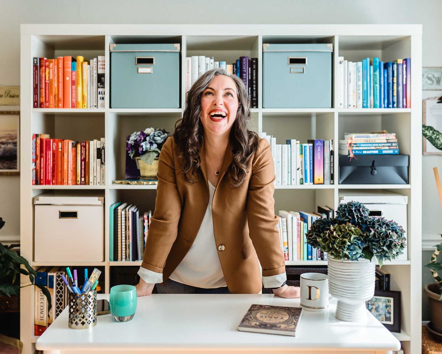 life and business coach standing at desk smiling during brand photo shoot