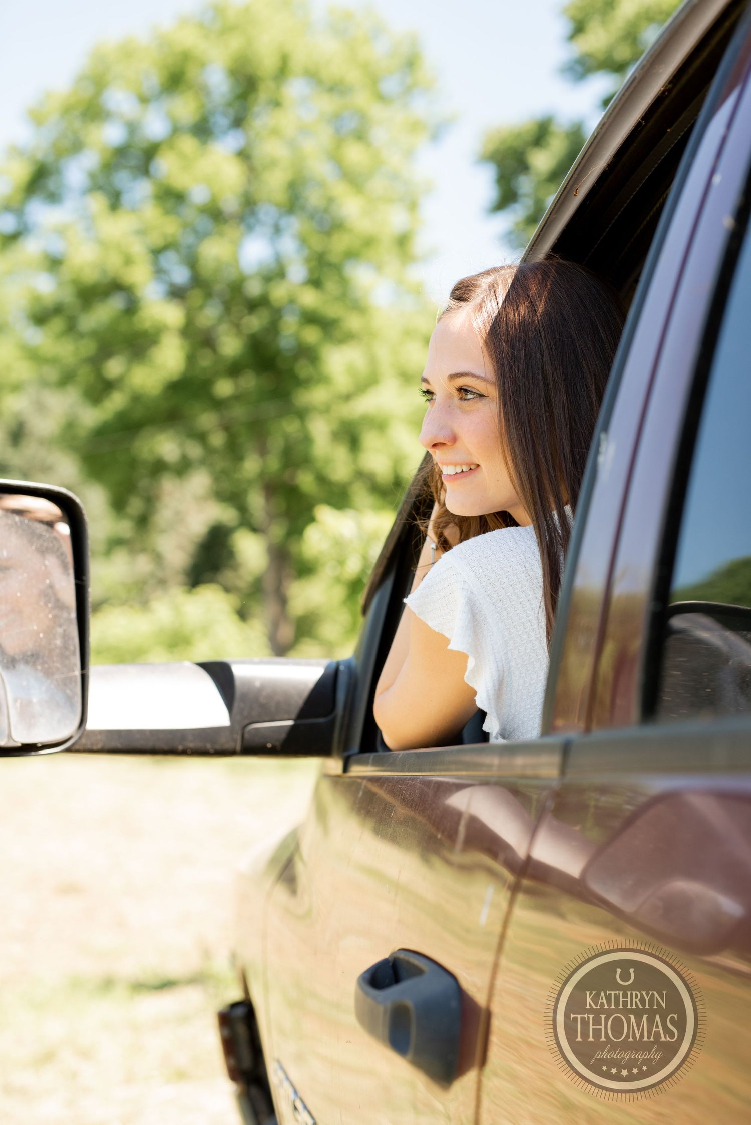 Side profile portrait of person in white shirt sitting in truck during sunny photoshoot.