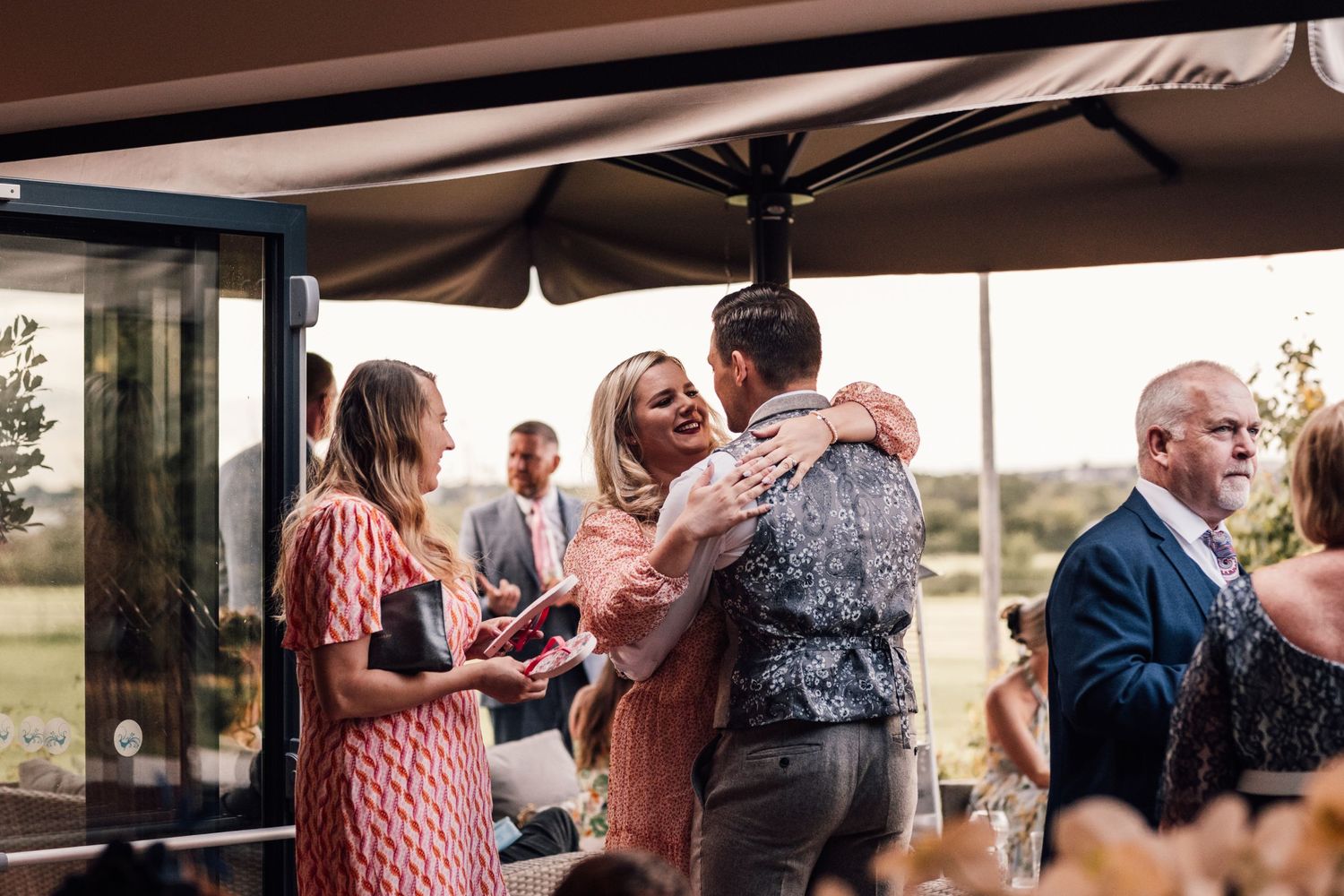 Wedding celebration with guests mingling under covered outdoor reception area.