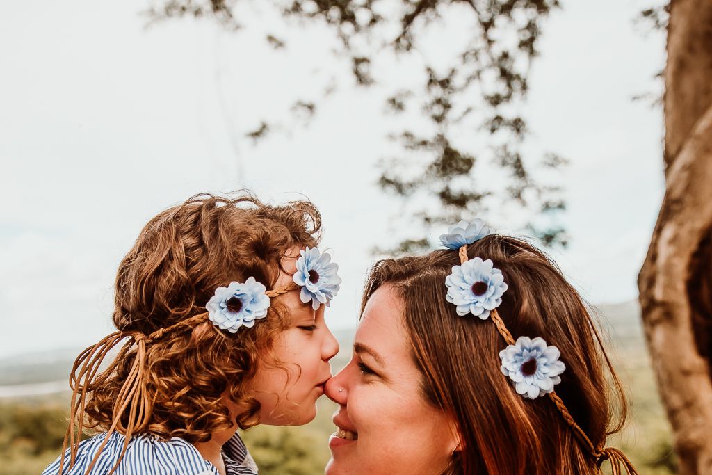 portrait of a cute little girl kissing her mom on the nose