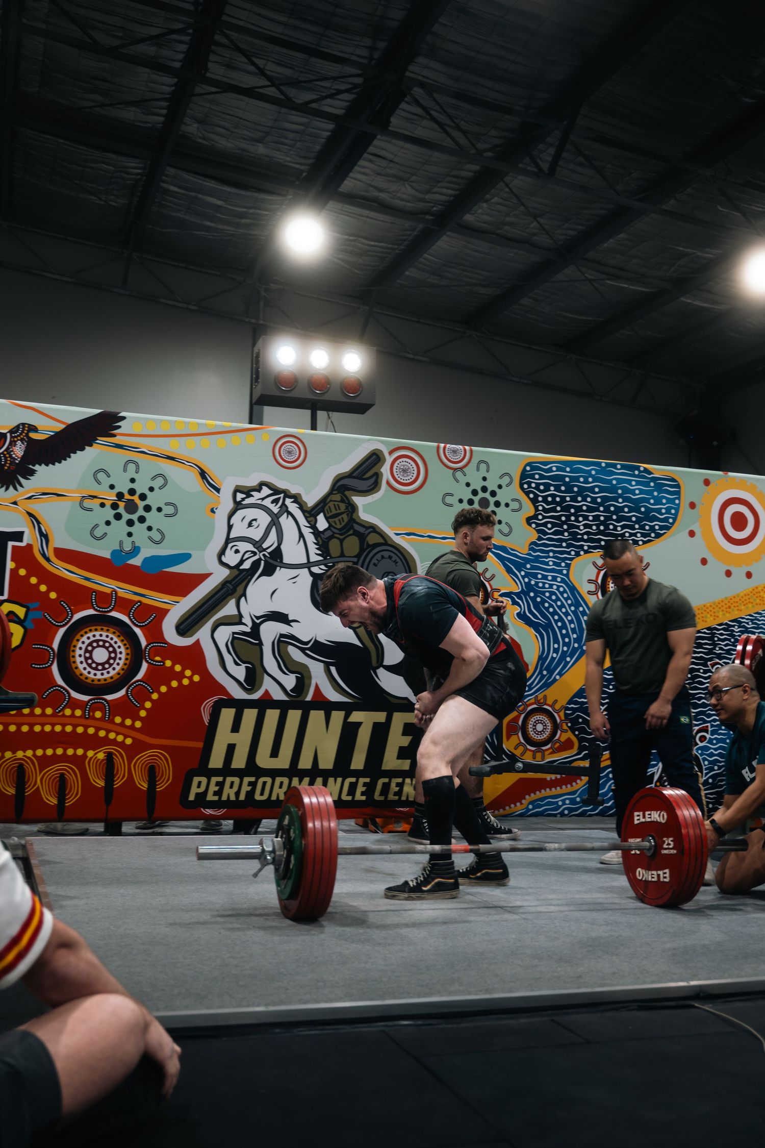 Weightlifter performing deadlift at Hunter Performance Center with colorful mural backdrop.