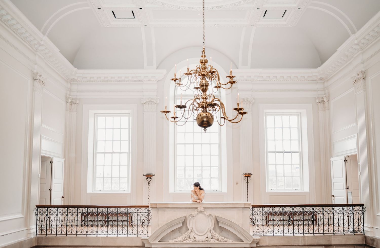 Elegant white ballroom interior featuring ornate chandelier and classic architectural details.