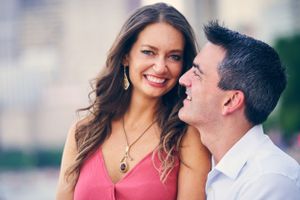 A romantic couple shares a joyful moment together outdoors while wearing pink and white.