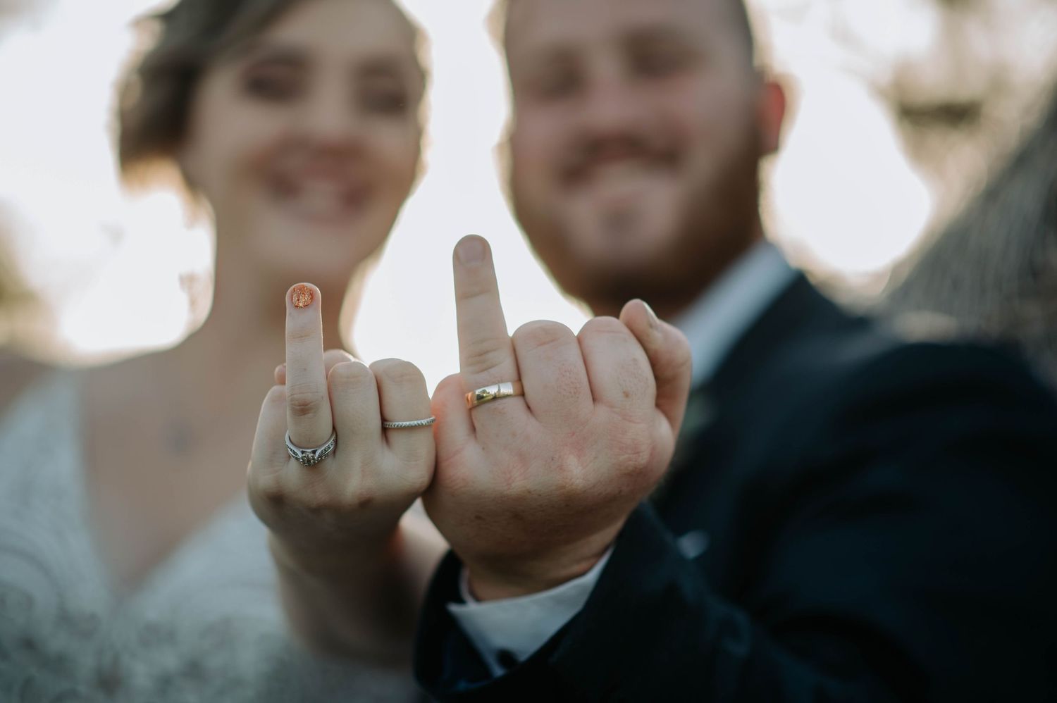 A creative wedding photo showing close up of wedding rings on fingers holding up a playful gesture.