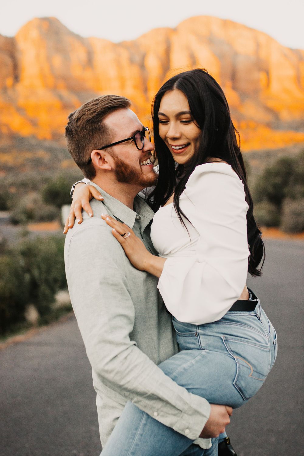 Candid engagement photos with couple laughing against golden mountain backdrop.