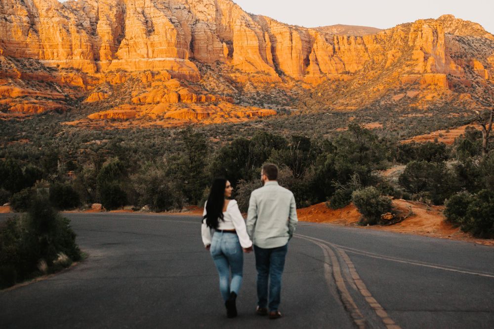 Desert landscape with towering red sandstone cliffs glowing in warm sunset light.