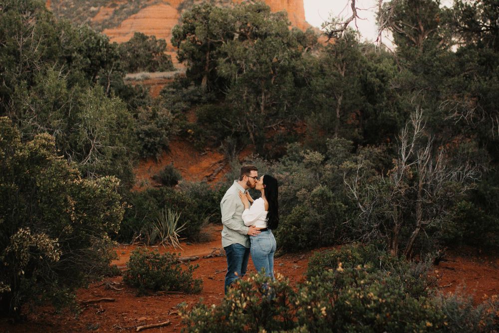 Desert engagement photoshoot among red rocks and desert vegetation.