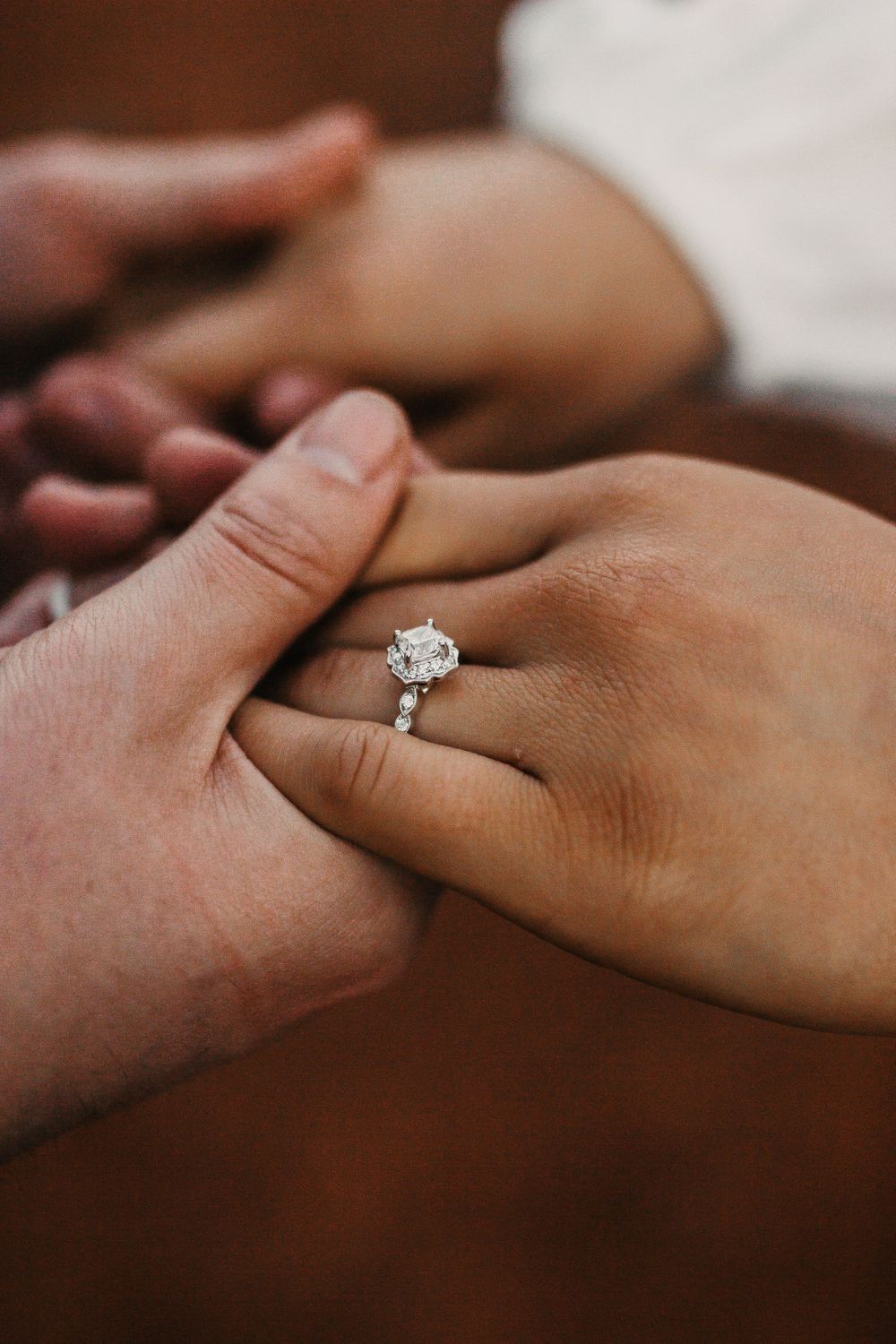 Close-up of hands with engagement ring showing tender moment.