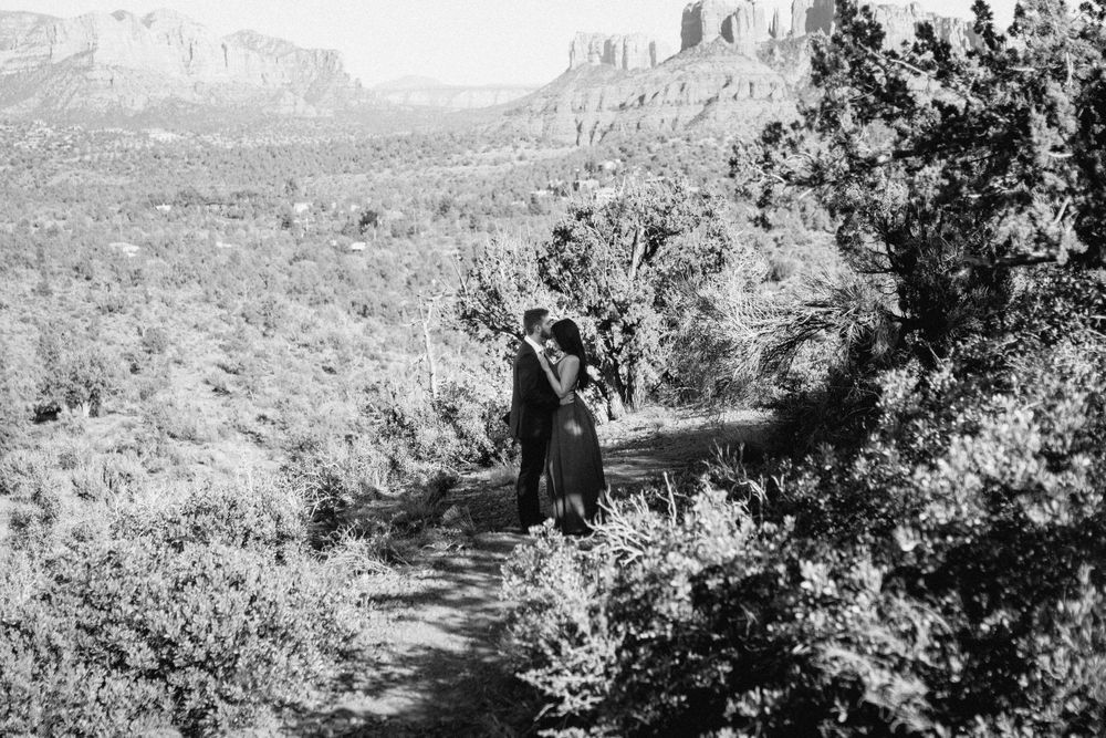 A black and white photo of someone walking on a desert trail surrounded by mountains.