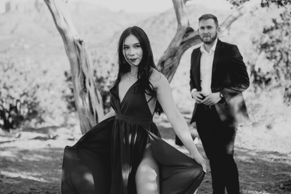 A black and white photo of a couple posing dramatically among trees.