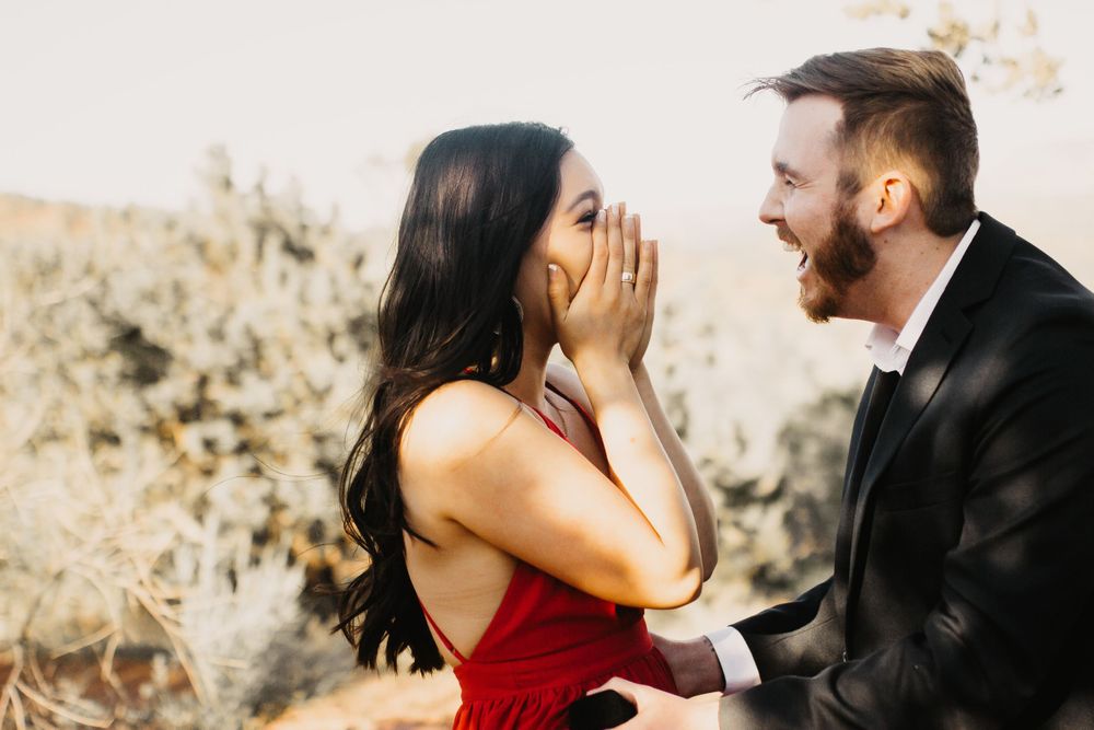 A couple shares joyful reactions during a surprise proposal in nature.